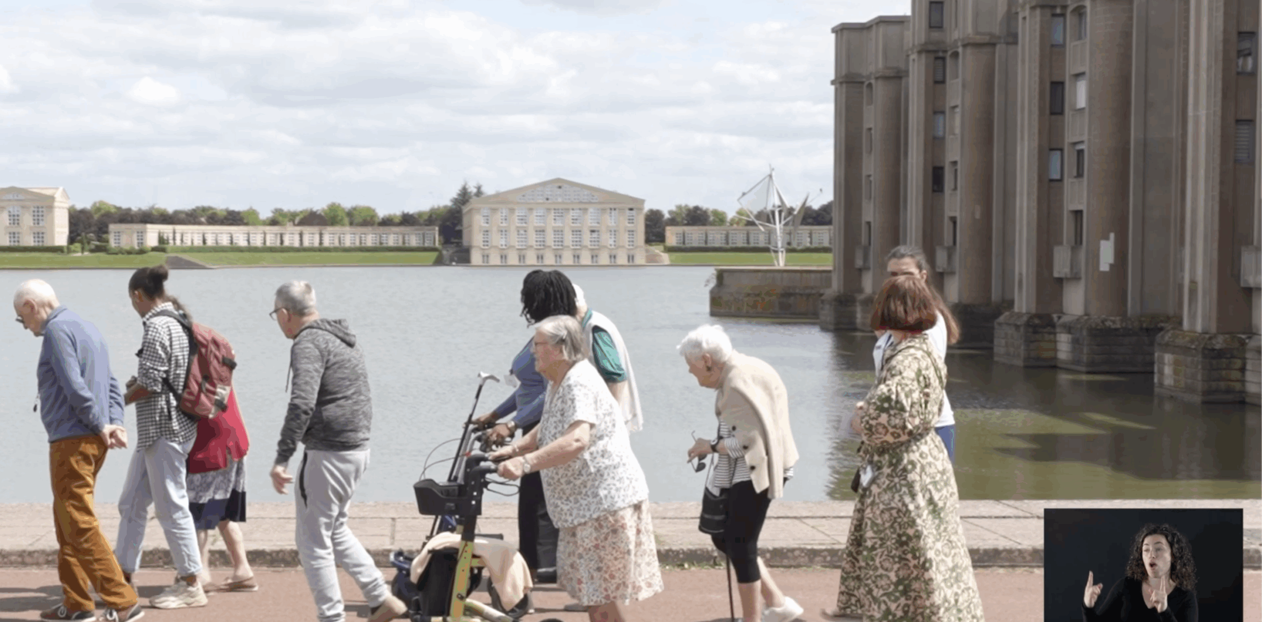 Un groupe de personnes âgées se promène au bord de l'eau dans un environnement urbain.